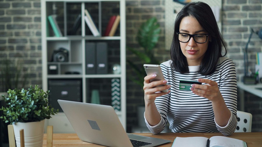 A woman in front of a laptop holding her credit card
